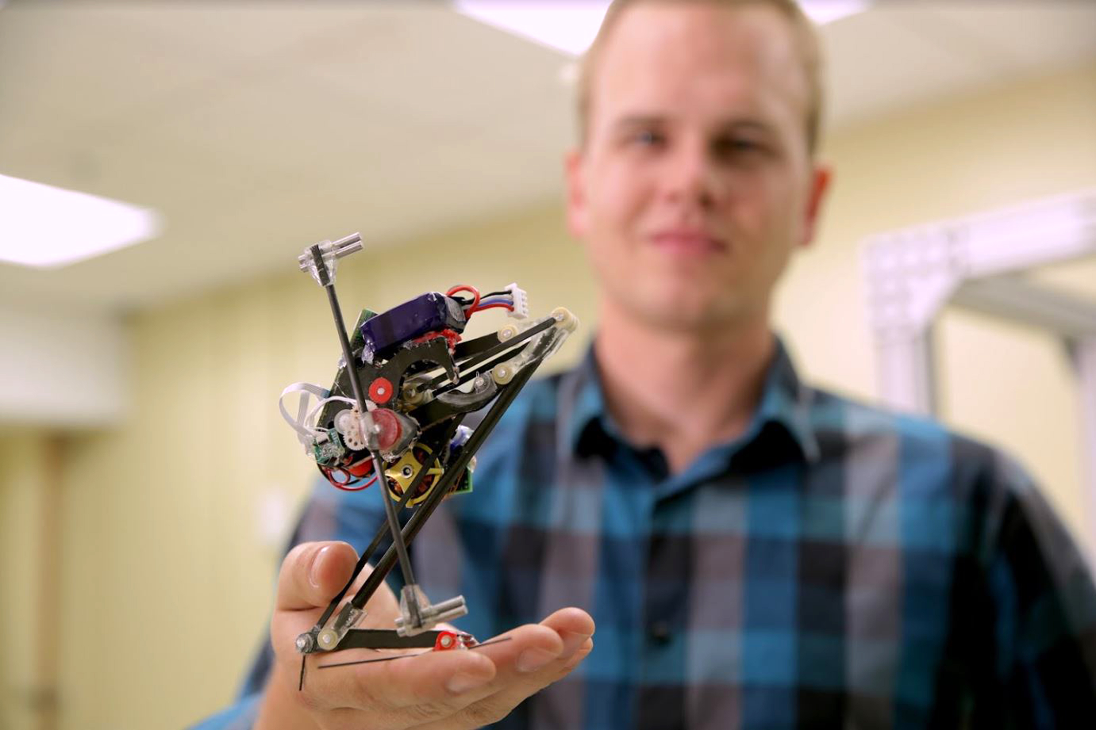 This handout provided December 6, 2016 by the University of Califonia at Berkeley in California shows researcher Duncan Haldane holding a robot known as Salto. An agile jumping robot that was inspired by some of the animal world's best leapers could one day help in rescue efforts after earthquakes or building collapses, US scientists said December 6. Salto, the 10-inch (26 centimeter) tall robot can jump higher than a bullfrog and almost as high as a galago, or bush baby, a small primate found in Africa. The robot can jump one yard (one meter) in less than one second, according to the report in the journal Science Robotics. That's better than a human but not the highest of any robot -- other machines have been made that can jump more than three meters in a single leap. Salto does hold the crown in vertical jumping agility, which researchers define as the ratio of the maximum jump height to the time it takes to complete one jump. / AFP PHOTO / UC BERKELEY / HO / RESTRICTED TO EDITORIAL USE - MANDATORY CREDIT "AFP PHOTO / UNIVERSITY OF CALIFORNIA BERKELEY" -NO SALES - NO MARKETING - NO ADVERTISING CAMPAIGNS - DISTRIBUTED AS A SERVICE TO CLIENTS - EDITORIAL USE TO ILLUSTRATE STORY ON SALTO ROBOT =