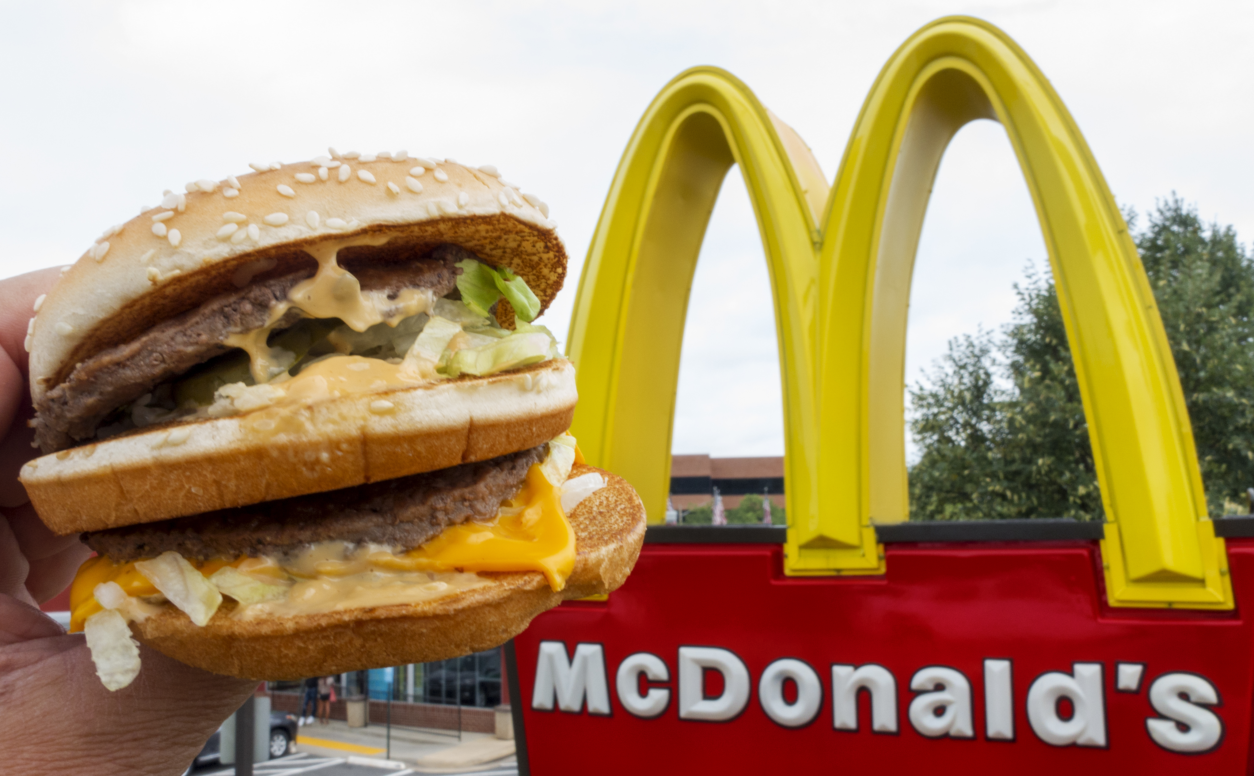 (FILES) This file photo taken on August 10, 2015 shows a McDonald's Big Mac held up near the golden arches at a McDonalds's in Centreville, Virginia.      McDonald's said December 8, 2016 it will shift its fiscal headquarters for the majority of non-US operations to Britain following an EU crackdown on the fast-food giant's tax benefits from Luxembourg. McDonald's is establishing a new Britain-based holding company to cover royalties from most licensing agreements outside the United States. The profits will be subject to British corporate taxes, McDonald's said.  / AFP PHOTO / PAUL J. RICHARDS