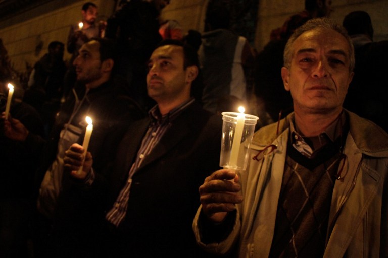 Egyptians carry candles during a vigil for the victims of a bomb explosion that targeted the Saint Peter and Saint Paul Coptic Orthodox Church on December 11, 2016, outside the Church in Cairo's Abbasiya neighbourhood. The blast killed at least 25 worshippers during Sunday mass inside the Cairo church near the seat of the Coptic pope who heads Egypt's Christian minority, state media said. / AFP PHOTO / SUHAIL SALEH