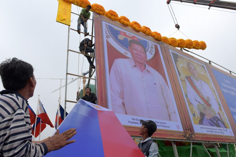 Cambodian workers assemble a display featuring the portrait of Philippine President Rodrigo Duterte (C) and Cambodian King Norodom Sihamoni (R) along a street in Phnom Penh on December 12, 2016. Duterte is scheduled to arrive in Cambodia on December 13 for a two-day state visit. / AFP PHOTO / TANG CHHIN SOTHY