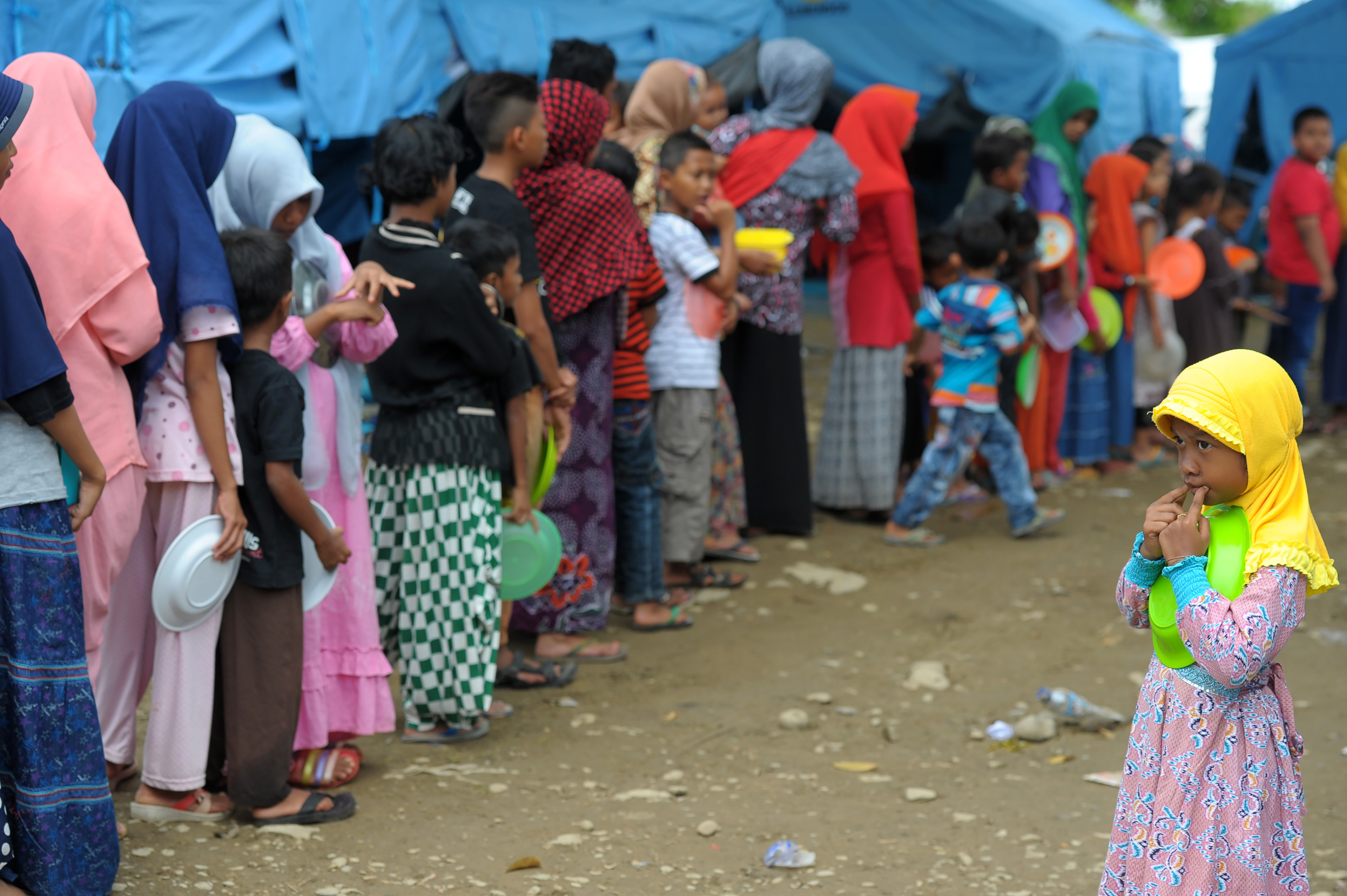 Acehnese displaced people queue for their meal at a shelter after 6.5 Magnitude earthquake in Pidie Jaya, Aceh province on December 12, 2016. Tens of thousands of people have been displaced after a devastating earthquake in Indonesia killed more than 100 people, an official said on December 10, leaving communities in ruins as aid trickled into the disaster-stricken province. / AFP PHOTO / CHAIDEER MAHYUDDIN