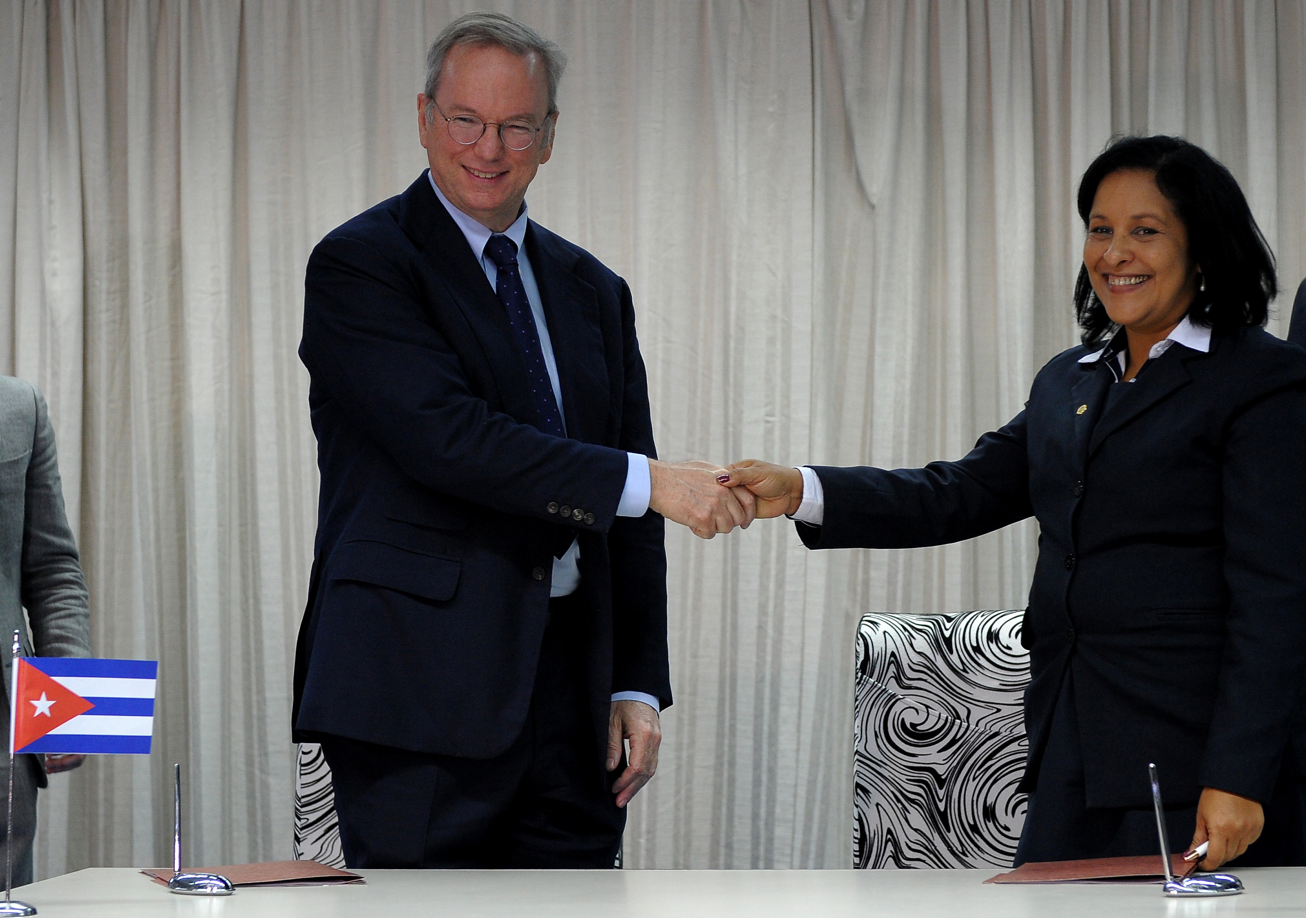 Google Executive Chairman Eric Schmidt (L) and Cuban national telecom provider (ETECSA) president executive Mayra Arevich shake hands after the signing of a bilateral agreement in Havana, on December 12, 2016.  / AFP PHOTO / YAMIL LAGE