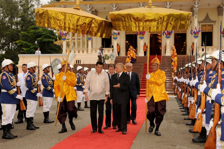 Philippines President Rodrigo Duterte (centre L) and Cambodian King Norodom Sihamoni (centre R) walk past honour guards during a meeting at the Royal Palace in Phnom Penh on December 14, 2016. Duterte is on a two-day state visit to Cambodia. / AFP PHOTO / STR / Cambodia OUT