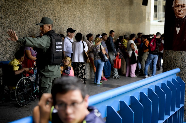 People queue outside Venezuela's Central Bank (BCV) in Caracas in an attempt to change 100 Bolivar notes, on December 16, 2016. Venezuelans lined up to deposit 100-unit banknotes before they turned worthless, but replacement bills had yet to arrive, increasing the cash chaos in the country with the world's highest inflation. Venezuelans are stuck in currency limbo after President Nicolas Maduro ordered the 100-bolivar note -- the largest denomination, currently worth about three US cents -- removed from circulation in 72 hours. / AFP PHOTO / FEDERICO PARRA