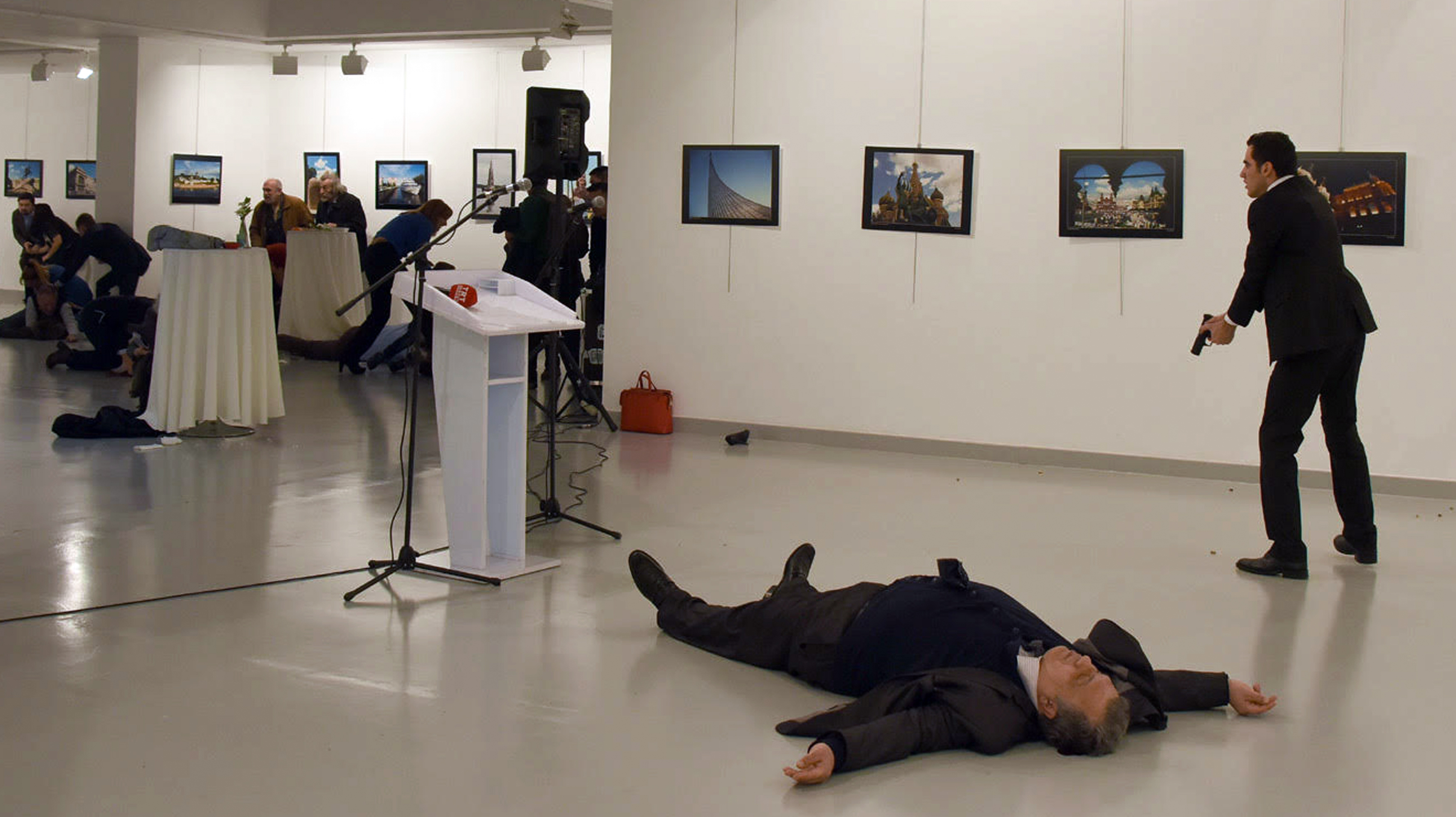 EDITORS NOTE: Graphic content / Andrey Karlov (front), the Russian ambassador to Ankara, lies on the floor next to his killer who still point his gun to people attending an art exhibition in Ankara, on December 19, 2016.  A gunman crying "Aleppo" and "revenge" shot Karlov while he was visiting an art exhibition in Ankara on December 19, witnesses and media reports said. The Turkish state-run Anadolu news agency said the gunman had been "neutralised" in a police operation, without giving further details. / AFP PHOTO / STRINGER
