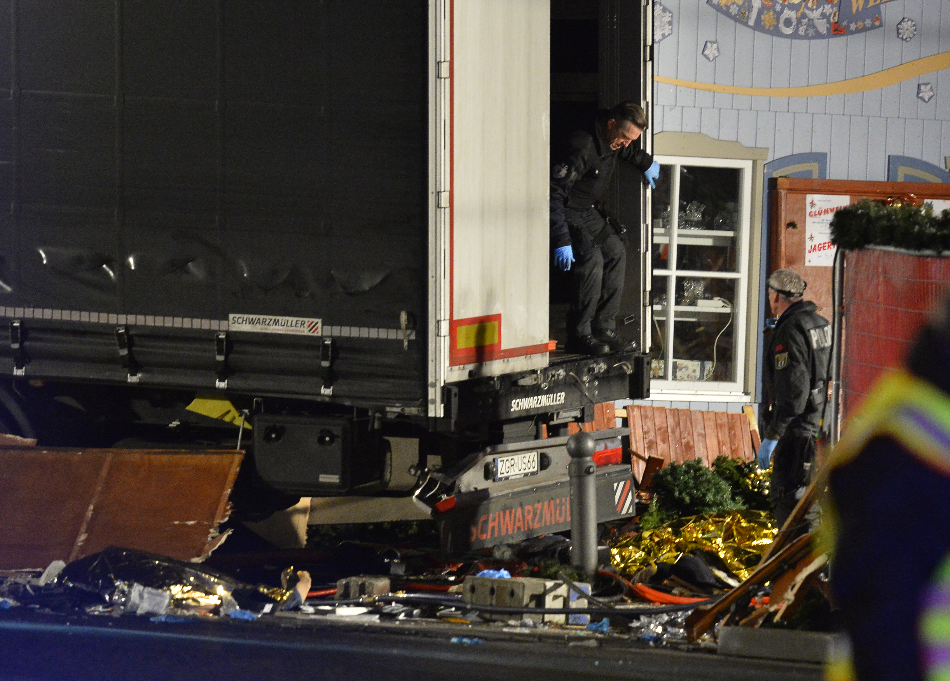 Policemen get of the truck that speeded into a christmas market in Berlin, on December 19, 2016 killing at least one person and injuring at least 50 people. Ambulances and heavily armed officers rushed to the area after the driver drove up the pavement of the market in a square popular with tourists, in scenes reminiscent of the deadly truck attack in the French city of Nice in July. / AFP PHOTO / John MACDOUGALL