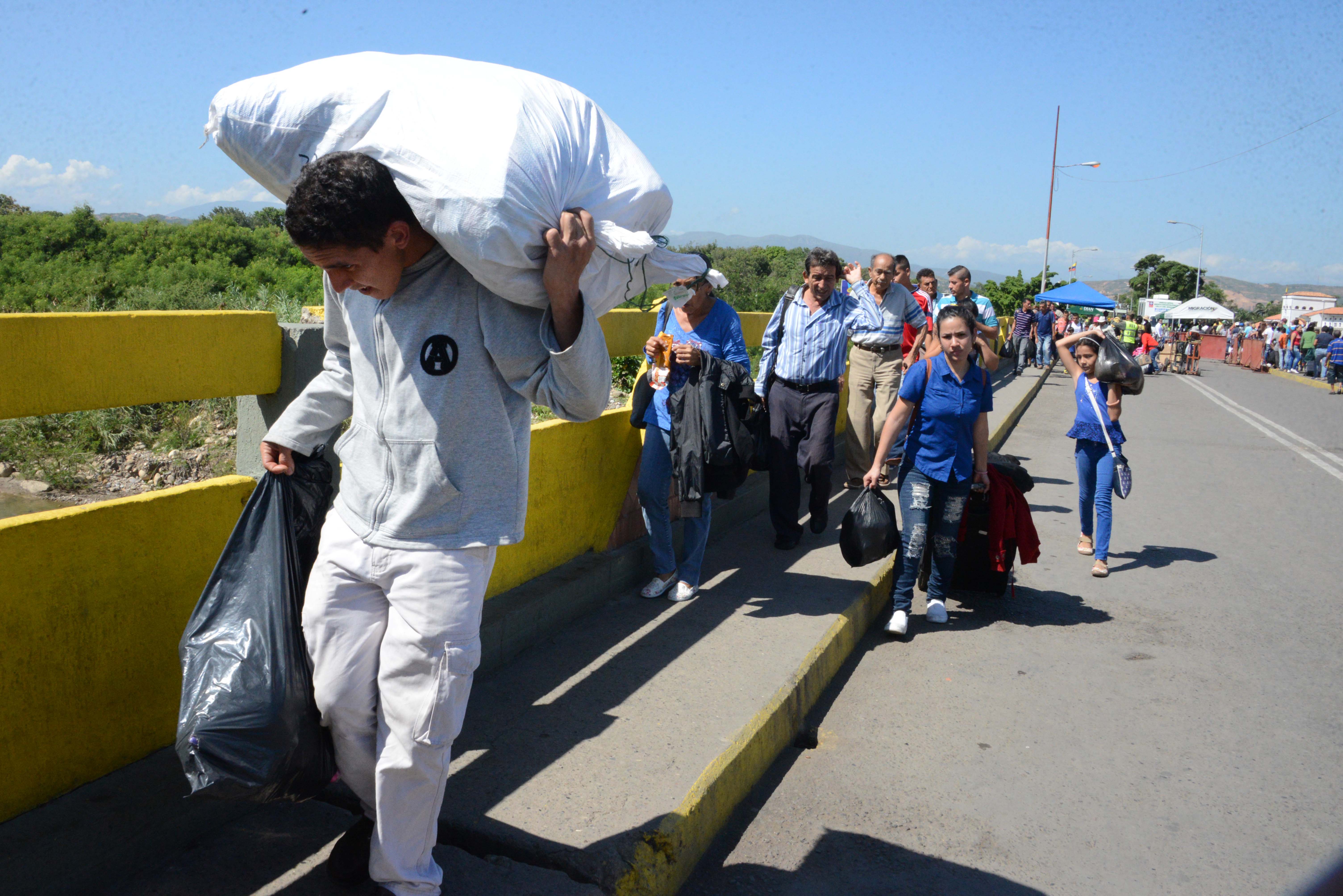 People cross the Simon Bolivar international bridge from San Antonio del Tachira, Venezuela to Norte de Santander province, Colombia, on December 20, 2016. Venezuela reopened Tuesday a border crossing with Colombia that it had closed as part of a messy crackdown on what it called currency hoarders. / AFP PHOTO / GEORGE CASTELLANOS