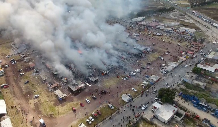 A massive explosion guts Mexico's biggest fireworks market in Mexico City, on December 20, 2016. The explosion killed at least 31 people and injured 72, authorities said. The conflagration in the Mexico City suburb of Tultepec set off a quick-fire series of multicolored blasts that sent a vast cloud of smoke billowing over the capital. / AFP PHOTO / Josue SOLANO