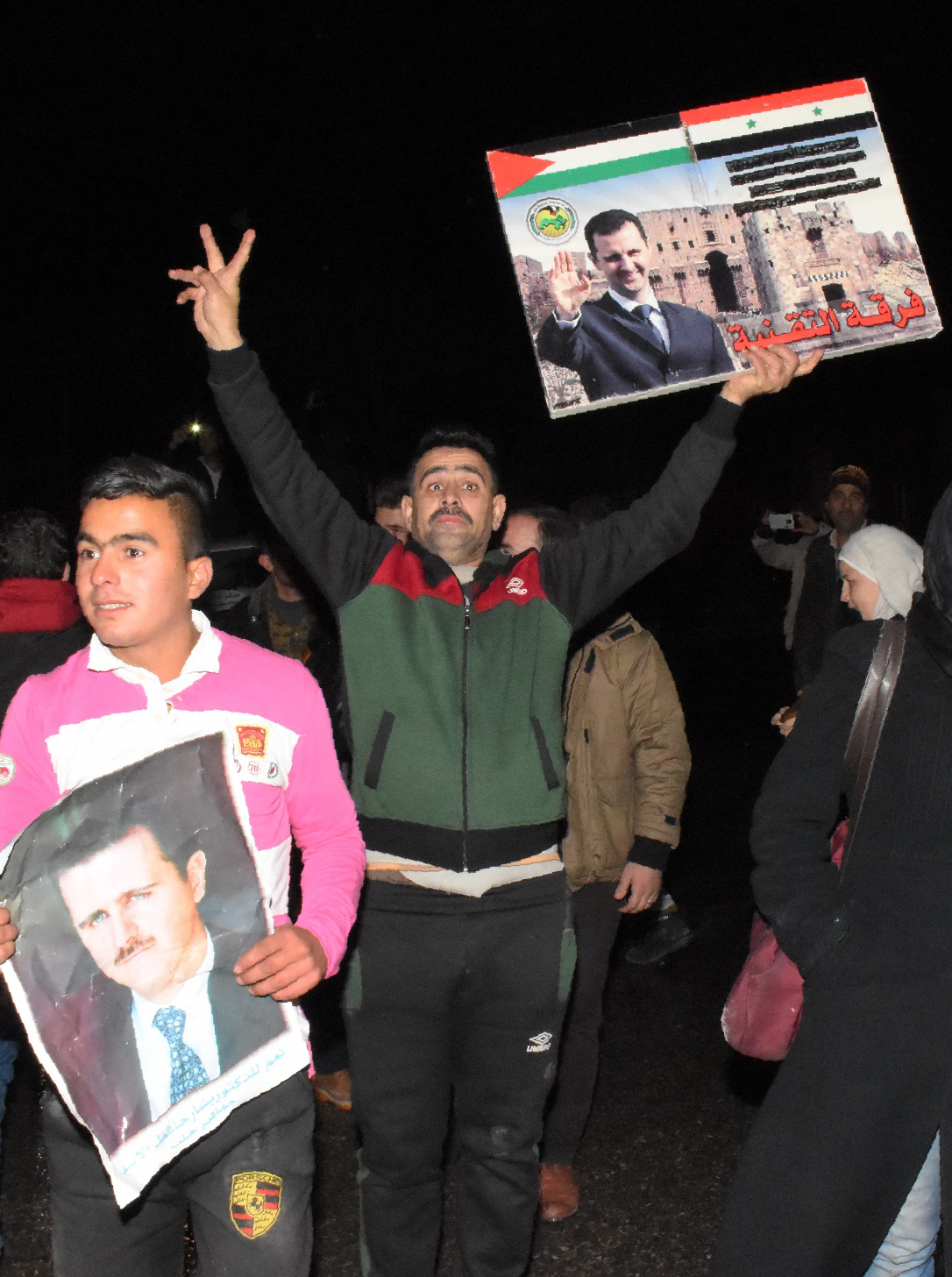 A Syrian man holds a placard bearing a portrait of Syrian President Bashar al-Assad as people celebrate in the streets on December 22, 2016 in the northern Syrian city of Aleppo, after the army said it has retaken full control of the country's second city The army said it has retaken full control of Syria's devastated second city Aleppo, scoring its biggest victory against opposition forces since the civil war erupted in 2011. / AFP PHOTO / George OURFALIAN