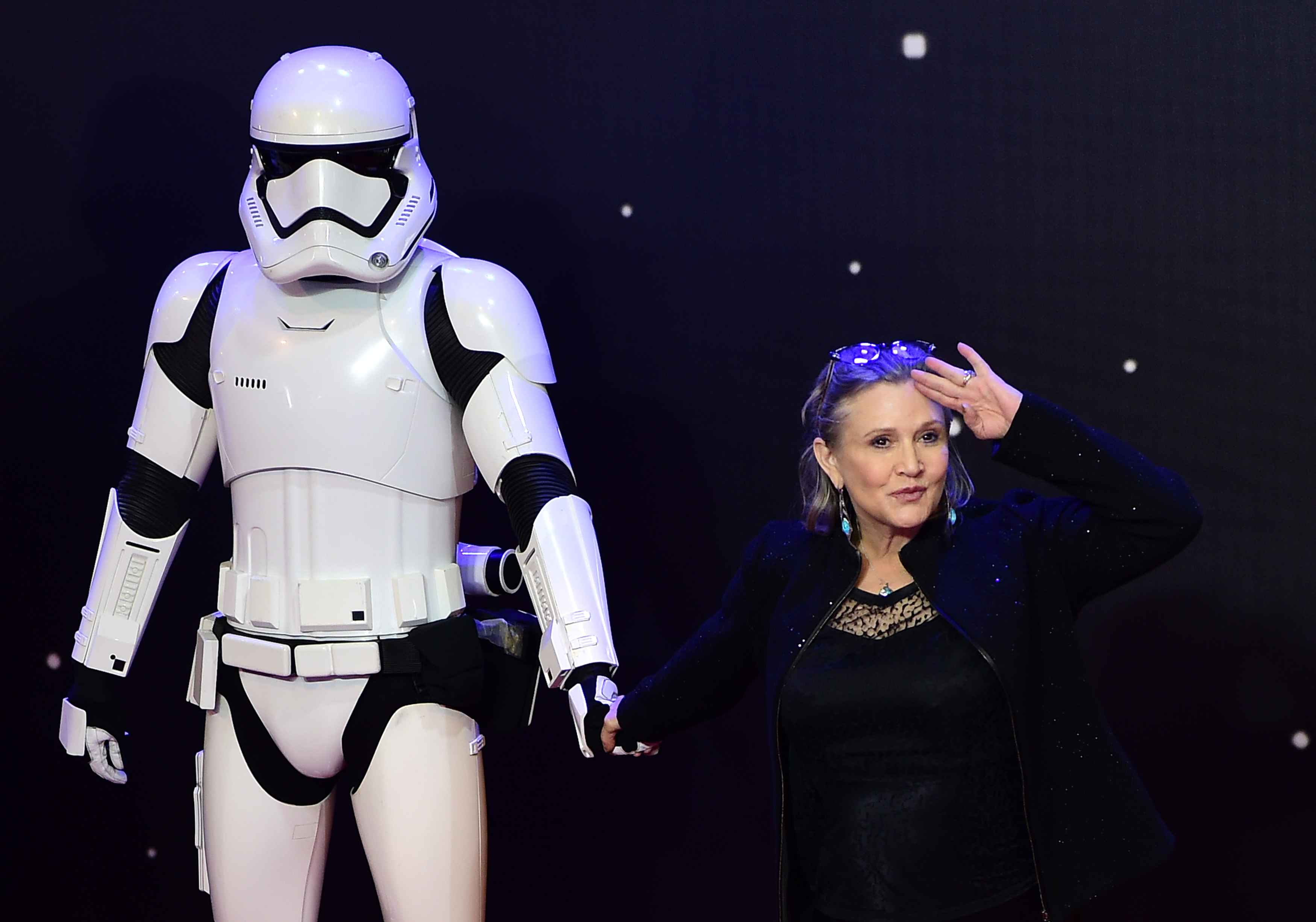 (FILES) This file photo taken on December 16, 2015 shows US actress Carrie Fisher (R) posing with a storm trooper as she attends the opening of the European Premiere of "Star Wars: The Force Awakens" in central London. Hollywood star Carrie Fisher was fighting for her life on December 23 after suffering a massive heart attack near the end of a transatlantic flight. The 60-year-old "Star Wars" actress was preparing to land in Los Angeles when she went into cardiac arrest, and was given cardiopulmonary resuscitation by an emergency responder on board.  / AFP PHOTO / LEON NEAL