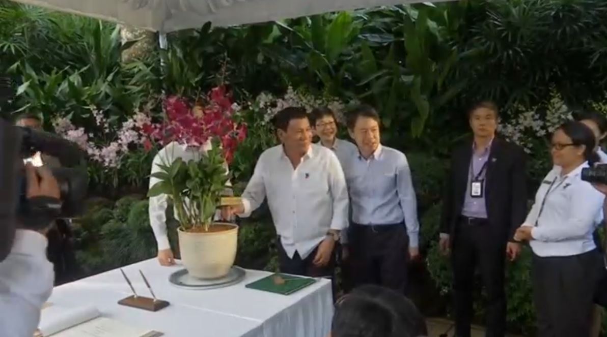 President Duterte poses for a photograph as he held the orchid, Dendrobium Rodrigo Roa Duterte, which was named by the Singaporean government in his honor (Photo grabbed from Reuters video).