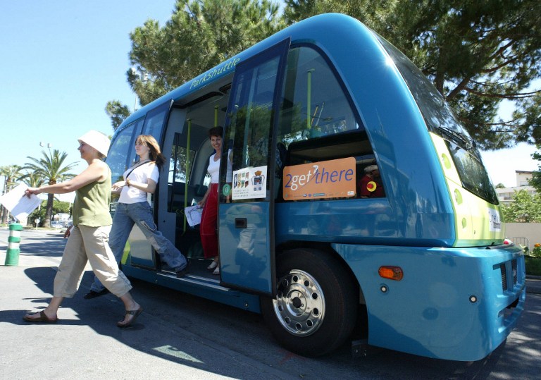 Passengers ride on the CyberCar in Antibes, southern France, 09 June 2004 where driverless minibus is being tested as part of the CyberMove project. The driverless minibus is a new form of public transport developed to improve the quality of life in cities by reducing use and parking needs of traditional cars as well as offering a cleaner and safer mode of transportation. The CyberCar travels at low speeds and follows a magnetized route. / AFP PHOTO / JACQUES MUNCH