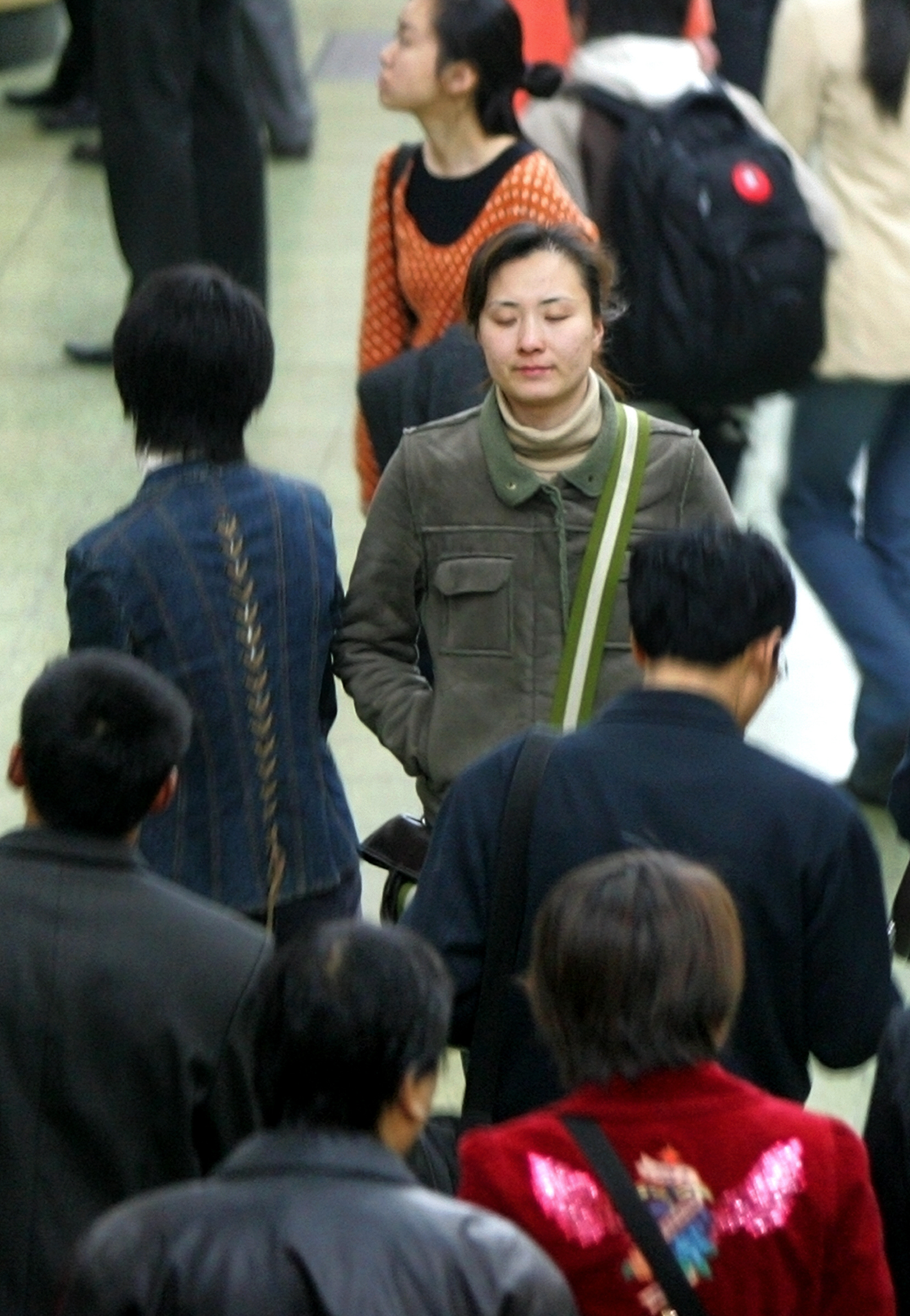 FILE PHOTO: A woman closes her eyes as pedestrians walk through a Beijing subway station, 01 April 2005. An estimated 100 million people, or eight percent of China's population, suffer from depression and most of them have received no treatment, state media reported. Experts say depression is one of China's most serious health threats, with a lack of public awareness and few services available to people who need treatment.  AFP PHOTO/Frederic J. BROWN / AFP PHOTO / FREDERIC J. BROWN