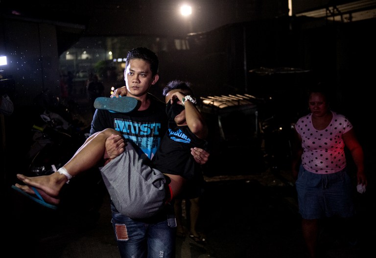 A man injured by a firecracker is carried by his relative as they arrive at the Jose Reyes Memorial Medical Center in Manila early on January 1, 2017, after new year's celebrations. / AFP PHOTO / NOEL CELIS