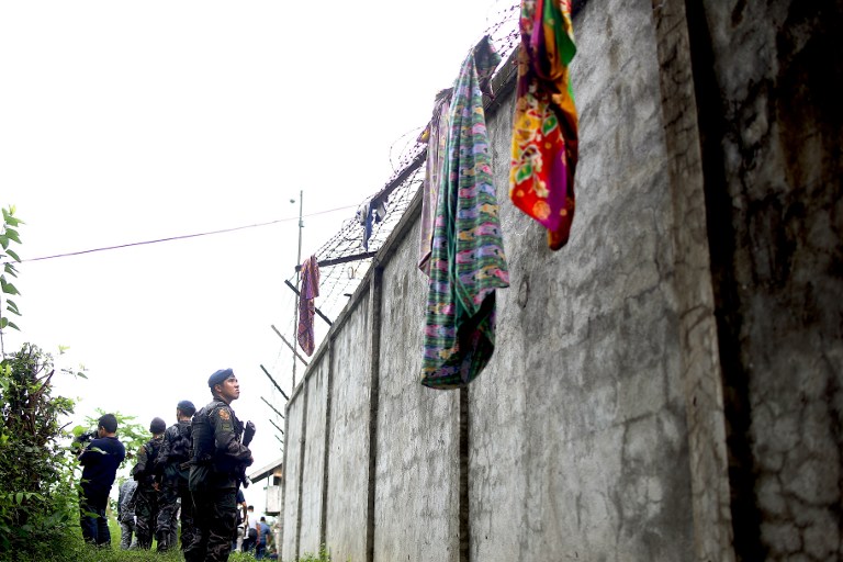 Armed police patrol along the perimeter fence of the district jail where more than a hundred inmates escaped in the town of Kidapawan on the southern island of Mindanao on January 4, 2017. More than 150 inmates of the southern Philippine jail escaped when suspected Muslim rebels stormed the dilapidated facility in a pre-dawn raid on Janaury 4, killing one guard, authorities said. / AFP PHOTO / FERDINANDH CABRERA