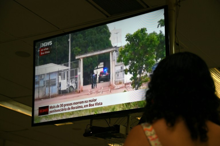 A woman watches on television news about the riot in the PAMC (Agricola de Monte Cristo Penitentiary) in Roraima, northern Brazil, on January 6, 2017 in Rio de Janeiro, Brazil. At least 33 inmates were killed by their rivals at a prison in northern Brazil on Friday, days after a riot by warring gangs left dozens more dead at another prison, officials said. / AFP PHOTO / VANDERLEI ALMEIDA