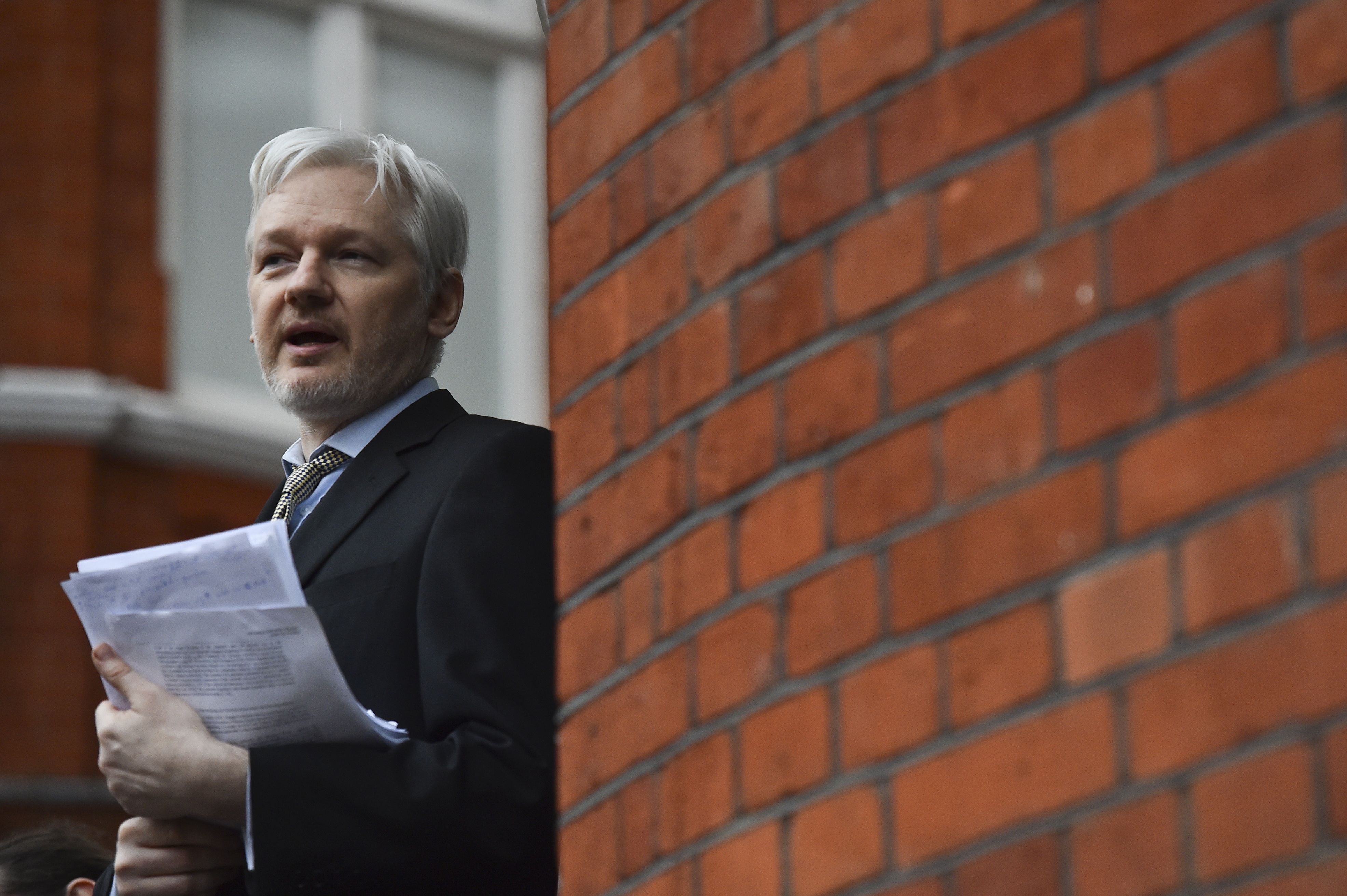 (FILES): This file picture taken on February 5, 2016 shows WikiLeaks founder Julian Assange addressing the media and holding a printed report of the judgement of the UN's Working Group on Arbitrary Detention on his case from the balcony of the Ecuadorian Embassy in central London. Accusations that Russia interfered with the US presidential election by leaking hacked documents via WikiLeaks have put a fresh spotlight on the crusading website's founder Julian Assange. / AFP PHOTO / BEN STANSALL