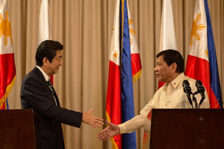 Philippine President Rodrigo Duterte (R) and Japanese Prime Minister Shinzo Abe (L) shake hands during a joint press statement at the Malacanang Palace in Manila on January 12, 2017. Prime Minister Abe arrived in the Philippines on January 12, becoming the first foreign leader to visit since President Rodrigo Duterte took office last year and launched his deadly war on crime. / AFP PHOTO / NOEL CELIS