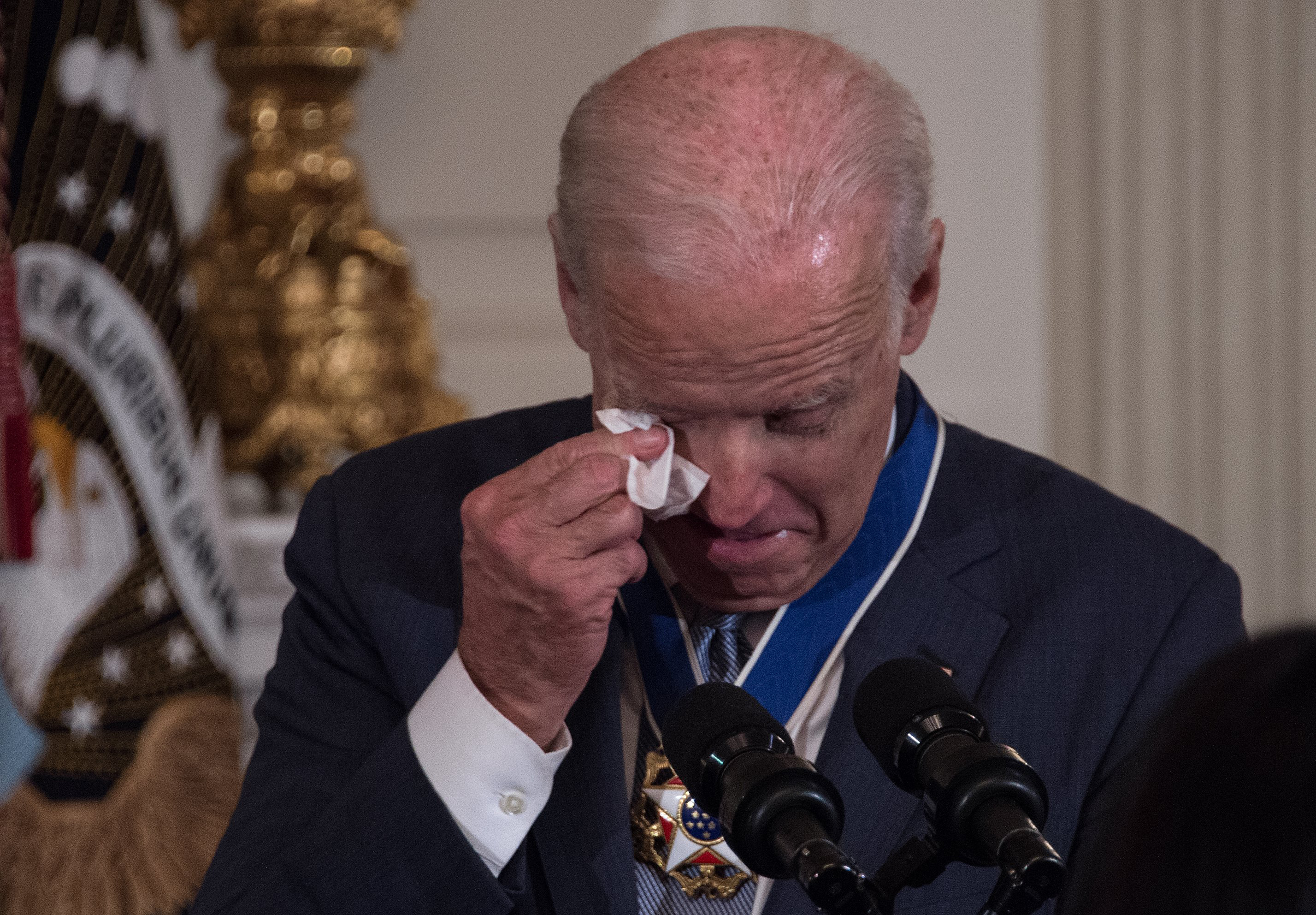 US Vice President Joe Biden wipes away tears after President Barack Obama awarded him the Presidential Medal of Freedom during a tribute to Biden at the White House in Washington, DC, on January 12, 2017. / AFP PHOTO / NICHOLAS KAMM