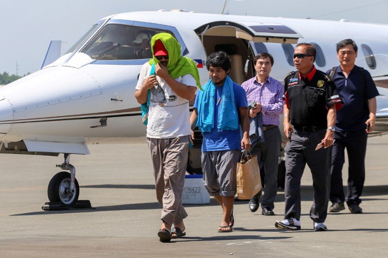 Captain Chul Hong Park (L), a South Korean national, and 2nd officer Filipino Glenn Alindajao (2 L), two hostages released in Jolo Sulu, arrive in Davao City with Philippine Peace Adviser Secretary Jesus Dureza (2nd R)on Jan 14, 2017.  A South Korean captain and a Filipino crewman abducted by suspected Islamist militants in the southern Philippines three months ago were released, the presidential peace adviser said. / AFP PHOTO / MANMAN DEJETO