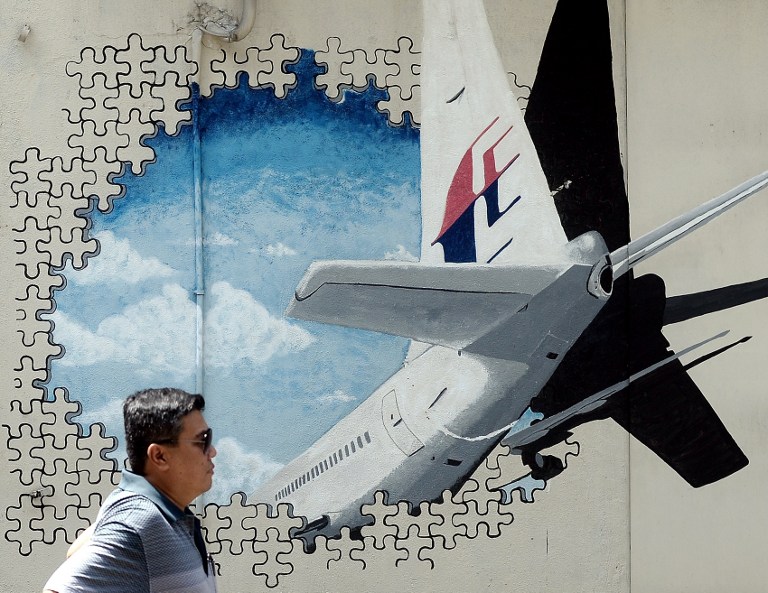 (FILES) This file picture taken on March 8, 2016 shows a man walking in front of a mural of missing Malaysia Airlines MH370 plane in a back-alley in Shah Alam.  The deep ocean hunt for missing passenger jet MH370 has been suspended after nearly three years without result, the Australian, Malaysian and Chinese governments said on January 17, 2017. / AFP PHOTO / MANAN VATSYAYANA