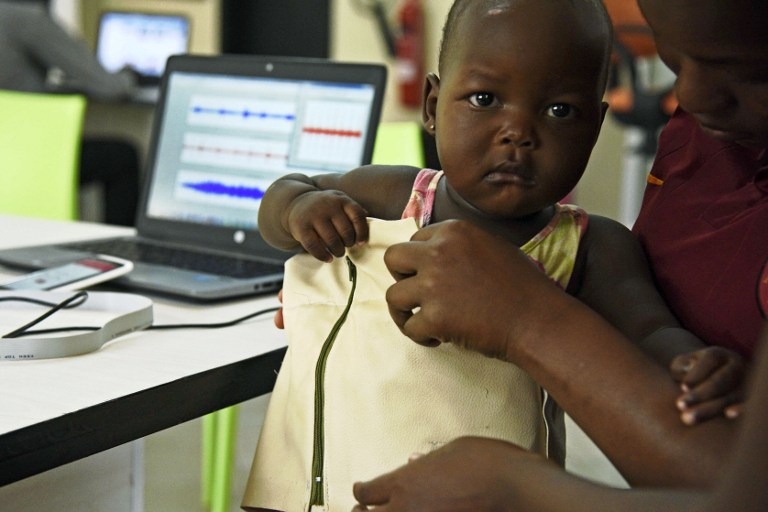 Telecommunications engineer Olivia Koburongo fits a child with the mama-ope kit at the Makerere University of Public Health in Kampala on January 16, 2017.  A team of Ugandan engineers has invented a "smart jacket" that diagnoses pneumonia faster than a doctor, offering hope against a disease which kills more children worldwide than any other. / AFP PHOTO / ISAAC KASAMANI