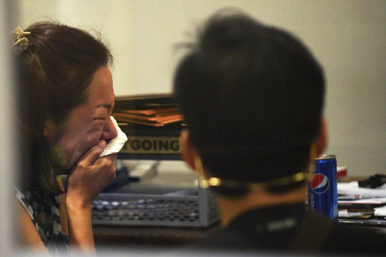 The wife (L) of a South Korean businessman, who was kidnapped and murdered by at least three police officers in the Philippines, cries as she talks with officials at the National Bureau of Investigation (NBI) headquarters in Manila on January 18, 2017. Philippine police kidnapped and murdered a South Korean businessman, then led his wife to believe he was alive for months to extort money from her, authorities said on January 18. / AFP PHOTO / Ted ALJIBE