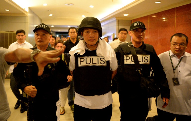 Police officer Ricky Sta. Isabel (C), one of the suspects in the kidnapping and murder of South Korean businessman Jee Ick Joo, is escorted by fellow policemen as they leave the National Bureau of Investigation (NBI) building in Manila on January 20, 2016. A South Korean businessman kidnapped by Philippine policemen under the guise of a raid on illegal drugs was murdered at the national police headquarters in Manila, authorities said Thursday. / AFP PHOTO / NOEL CELIS