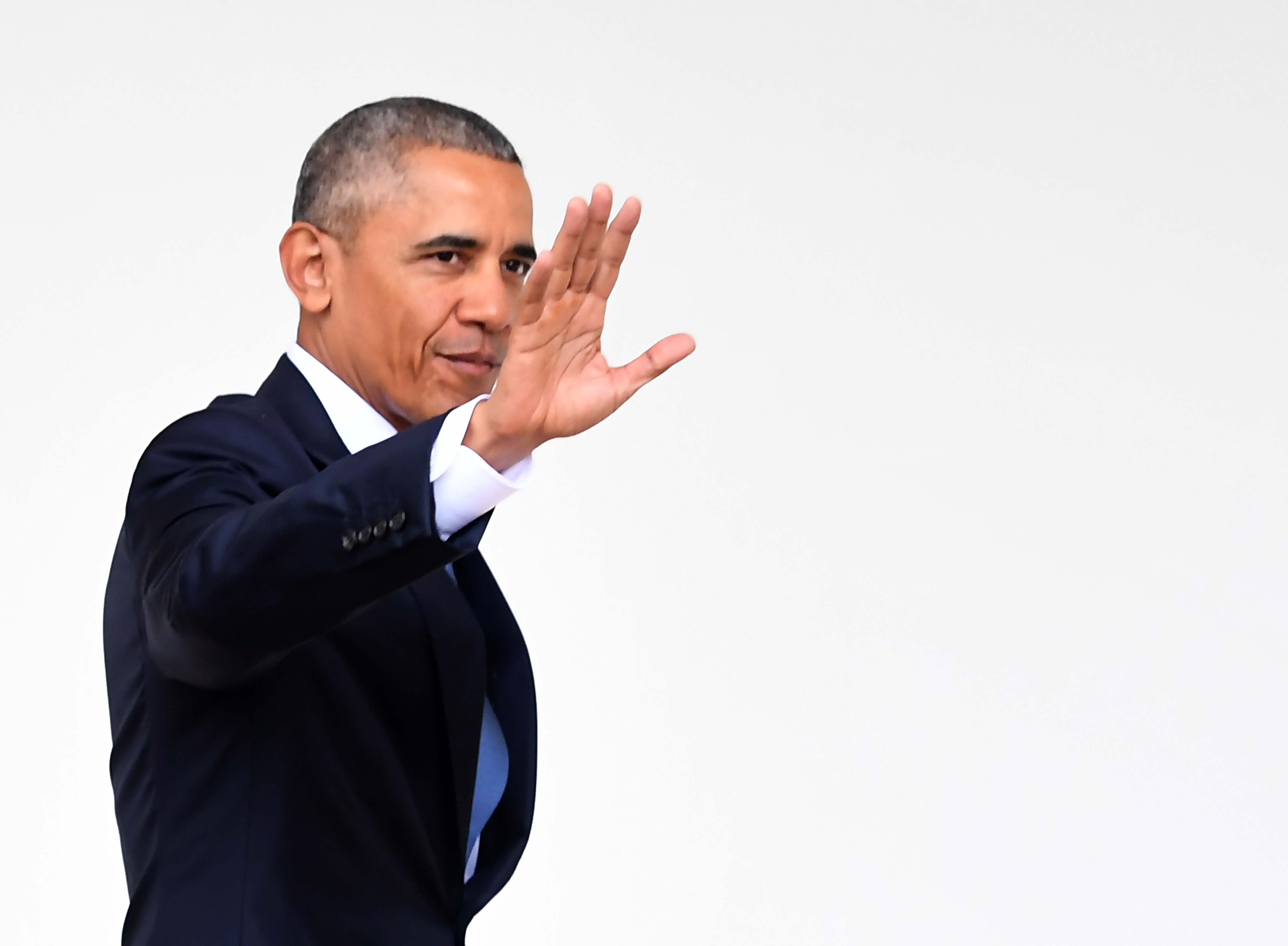 US President Barack Obama waves as he walks through the colonnade as he departs the Oval Office for the last time as president, at the White House in Washington, DC January 20, 2017. / AFP PHOTO / JIM WATSON