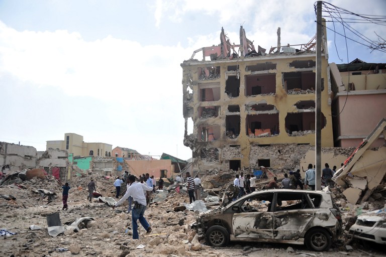 People react and walk among rubbles following an attack outside an hotel on January 25, 2017, in Mogadishu. At least seven people were killed after two car bombs exploded outside a popular Mogadishu hotel and gunmen forced their way inside the building and opened fire, police said. The attack, claimed by the Al-Qaeda aligned Shabaab insurgent group, began when a car loaded with explosives rammed the gate of the Dayah Hotel near the Somali parliament and state house. Gunmen then stormed the hotel and exchanged fire with security guards, according to police official Ibrahim Mohammed. / AFP PHOTO / MOHAMED ABDIWAHAB