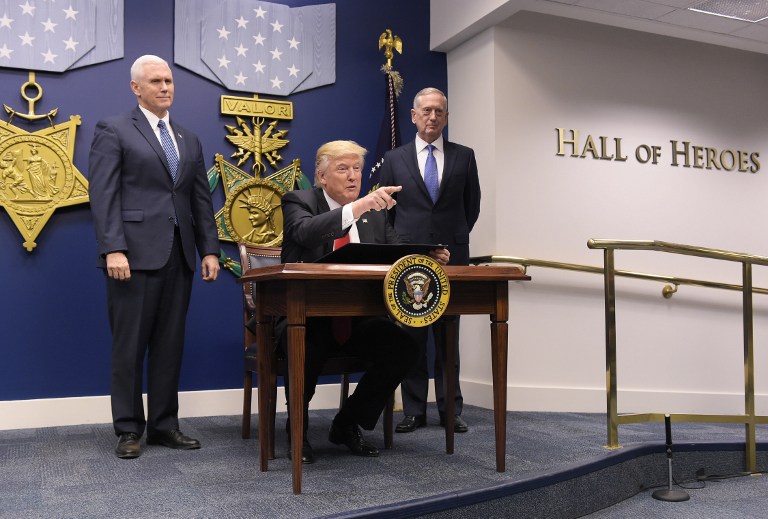 US President Donald Trump gestures before signing an executive action on rebuilding the armed forces on January 27, 2017 at the Pentagon in Washington, DC. Looking on are US Vice President Mike Pence (L) and US Defense Secretary James Mattis. / AFP PHOTO / MANDEL NGAN
