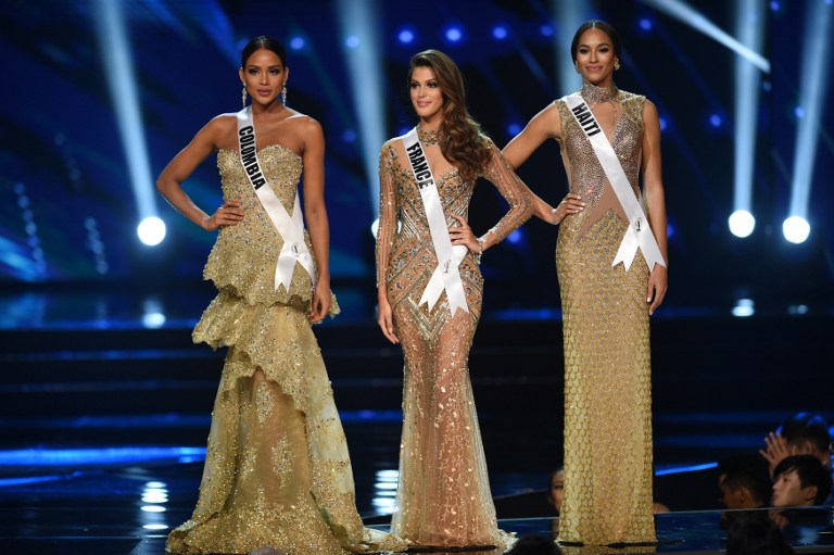 Miss Universe candidates (L to R) Andrea Tovar of Colombia, Iris Mittenaere of France and Raquel Pelissier of Haiti stand on stage as they wait for the announcement of the winner during the finals of the Miss Universe pageant at the Mall of Asia Arena in Manila on January 30, 2017. Miss France was crowned Miss Universe on January 30 in a glitzy spectacle free of last year's dramatic mix-up but with a dash of political controversy as finalists touched on migration and other hot-button global issues. / AFP PHOTO / TED ALJIBE