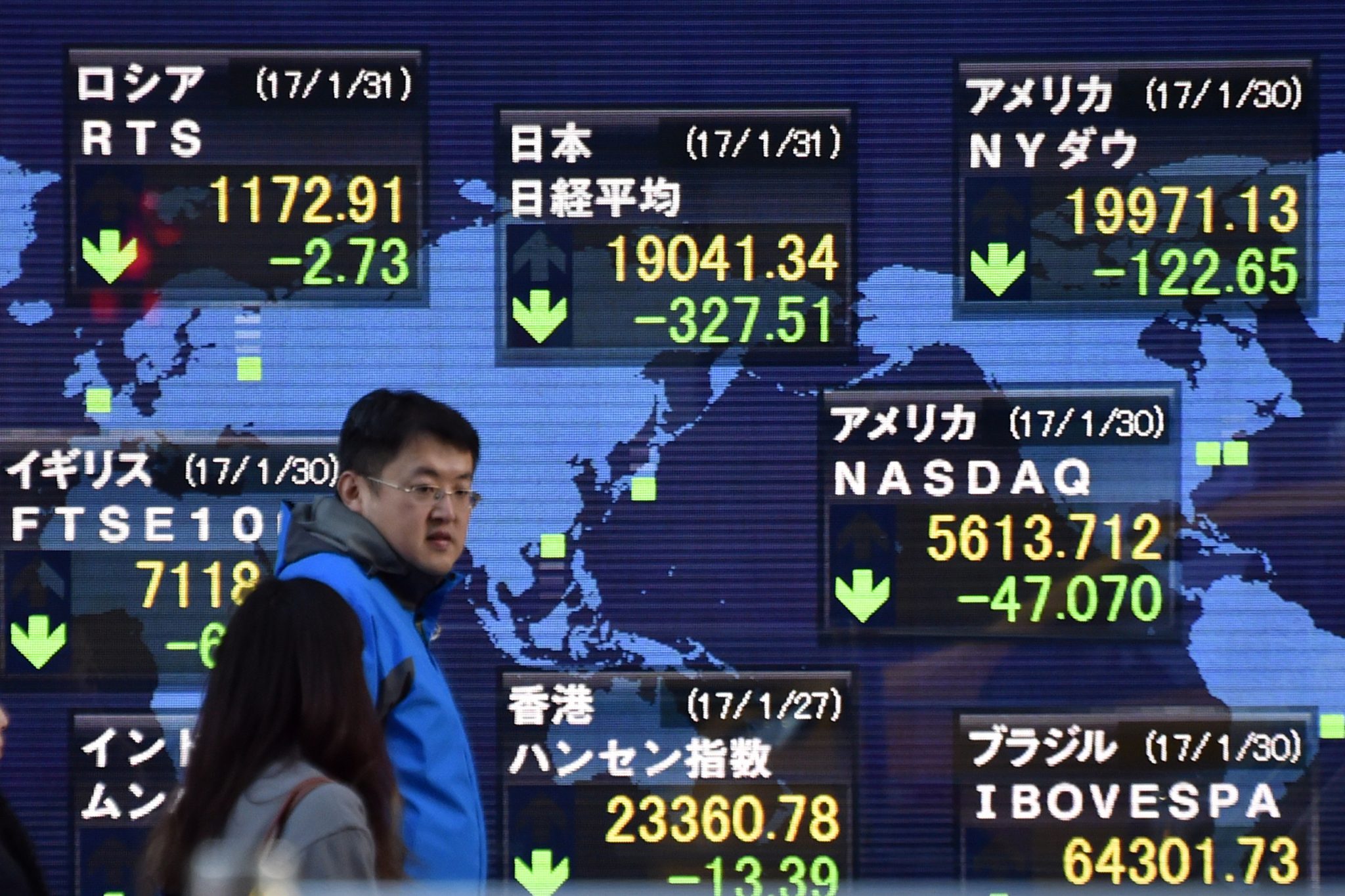 (FILES) This file photo taken on January 31, 2017 shows  Pedestrians walk in front of an electric quotation board flashing share prices of the world, including the Nikkei key index of the Tokyo Stock Exchange (top C), in Tokyo on January 31, 2017.  Asian markets edged down as dealers moved cautiously on February 3, 2017 following another tepid lead from Wall Street while focus shifts to the release later in the day of US jobs figures. / AFP PHOTO / Kazuhiro NOGI