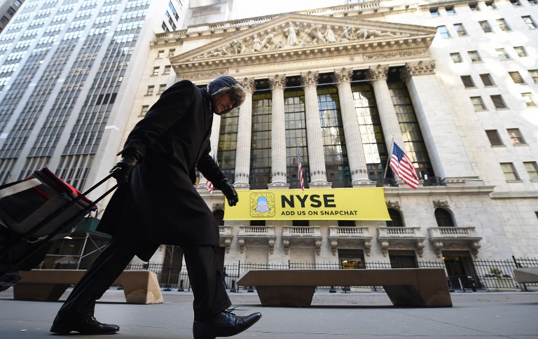 (FILES) This file photo taken on January 25, 2017 shows a person walking past the New York Stock Exchange on Wall Street in New York.  Wall Street stocks rose early on February 3, 2017 on a solid US jobs report as shares of large banks rallied on news the Trump administration will roll back financial regulations. The January US employment report included a better-than-expected 227,000 new jobs last month, keeping up the positive trends from the Obama years into the start of the term of President Donald Trump.Large banks such as JPMorgan Chase and Bank of America rose almost two percent as administration officials signaled that Trump will order a review of the Dodd-Frank law enacted after the 2008 financial crisis.  / AFP PHOTO / TIMOTHY A. CLARY