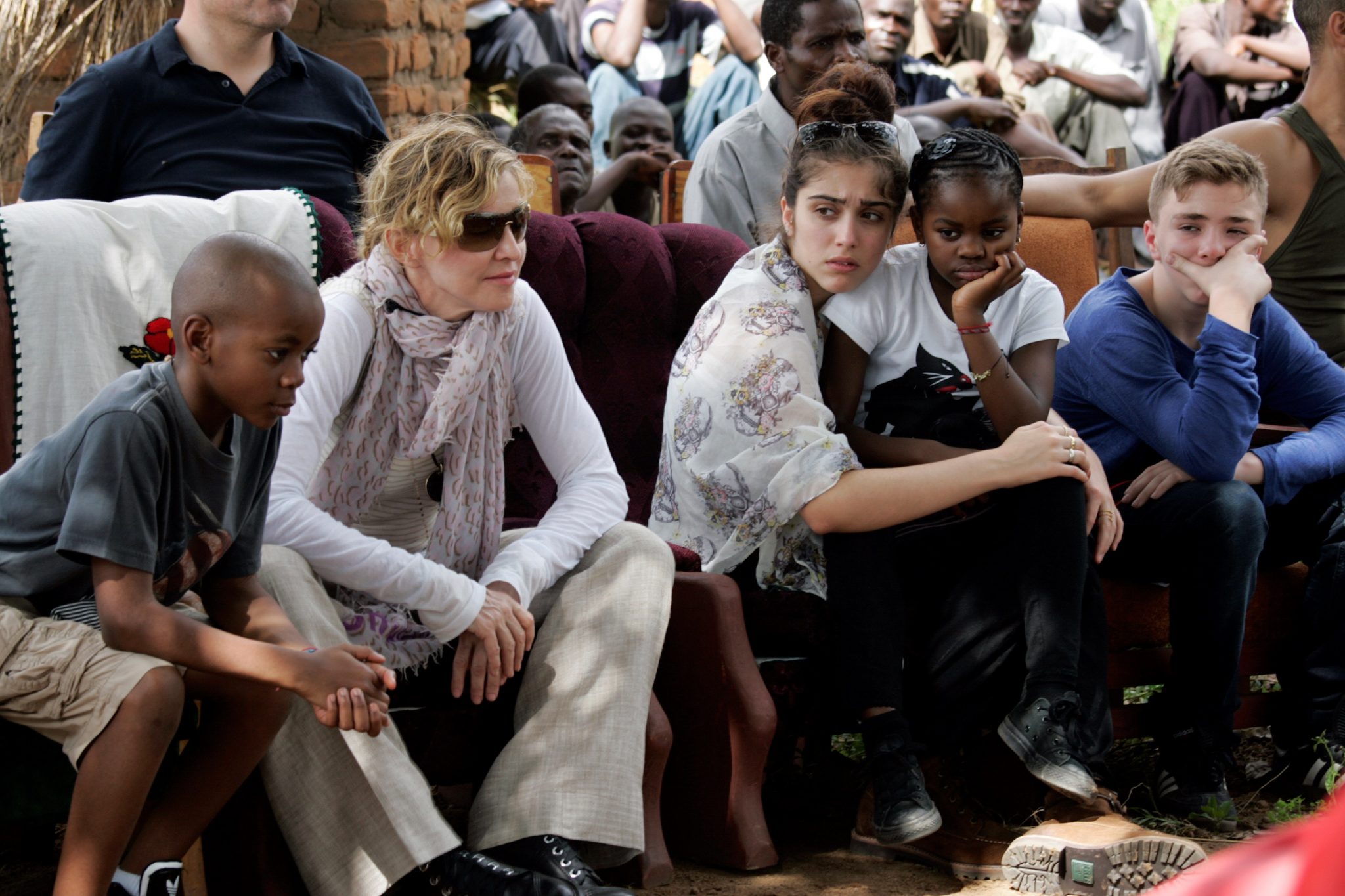 (FILES) This file photo taken on April 2, 2013 shows US Pop Star Madonna (2nd L) sitting with her biological and adopted children (L to R) David Banda, Lourdes, Mercy James, and Rocco at Mkoko Primary School, one of the schools Madonna's Raising Malawi organization has built jointly with US organization BuildOn, during a visit in the region of Kasungu, central Malawi.  A court in Malawi on February 7, 2017 approved Madonna's request to adopt two four-year-old twin girls, adding to the two other children that the US pop superstar adopted previously from the country. / AFP PHOTO / AMOS GUMULIRA