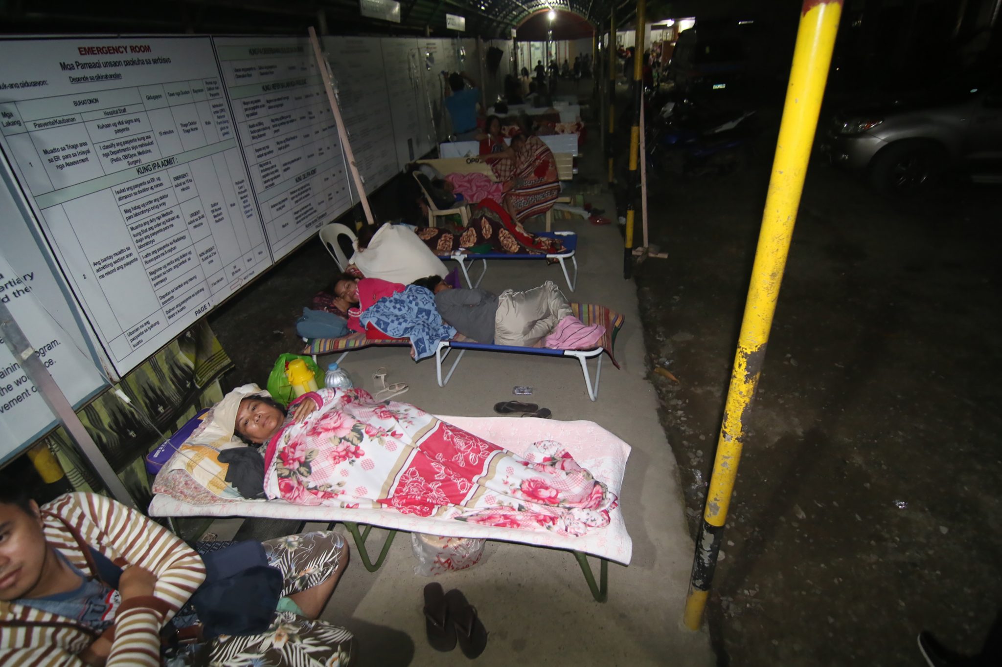 Hospital patients take shelter in a pedestrian-waiting shed for safety after a 6 .5-magnitude earthquake struck overnight in Surigao City, in southern island of Mindanao, February 11, 2017. A strong quake shook the southern Philippines on February 10, killing at least three people, toppling buildings and sending panicked residents fleeing their homes, media reports and authorities said. / AFP PHOTO / ERWIN MASCARINAS