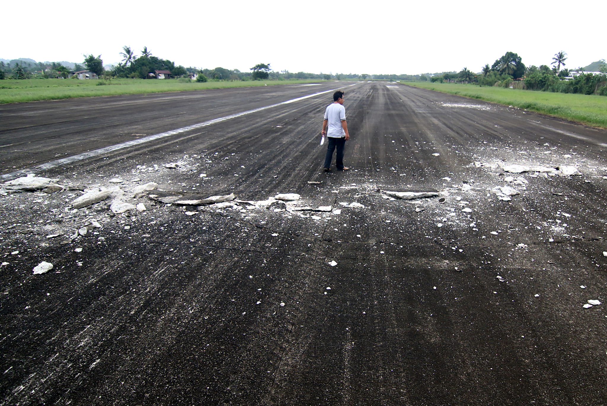 A man walks past the damaged runway of the dometic airport after a 6.5-magnitude earthquake struck overnight in Surigao City in southern island of Mindanao on February 11, 2017. A strong quake shook the southern Philippines on February 10, killing at least three people, toppling buildings and sending panicked residents fleeing their homes, media reports and authorities said. / AFP PHOTO / ERWIN MASCARINAS