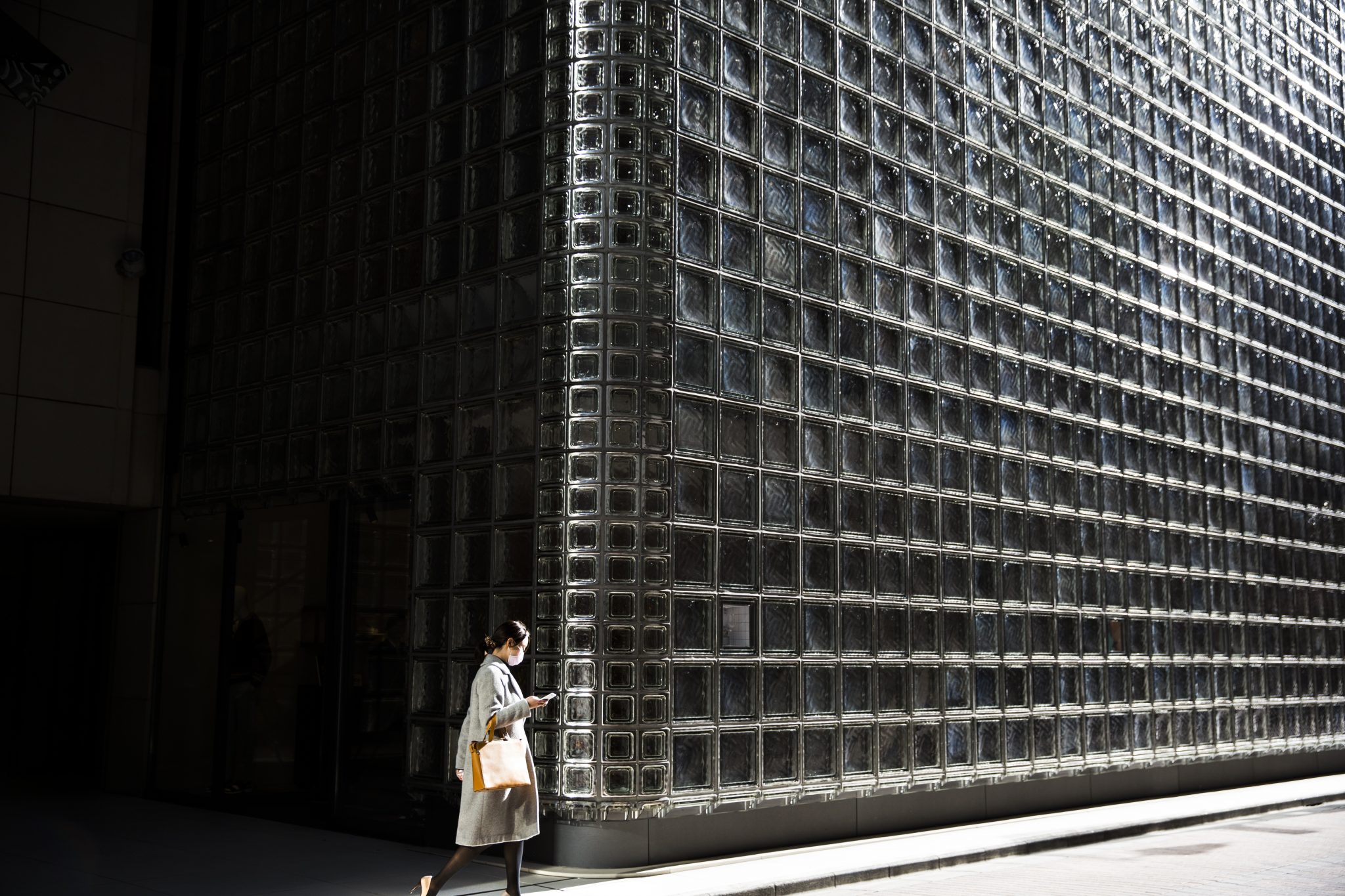 A woman walks out of the Maison Hermes building designed by Italian architect, Renzo piano, in the Ginza shopping district in Tokyo on February 13, 2017. Japan's economy expanded 1.0 percent in 2016 as a bump in exports and capital investment offset weak spending at home, data showed on February 13, 2017, although it was unlikely to erase concerns about Tokyo's faltering war on deflation. / AFP PHOTO / Behrouz MEHRI