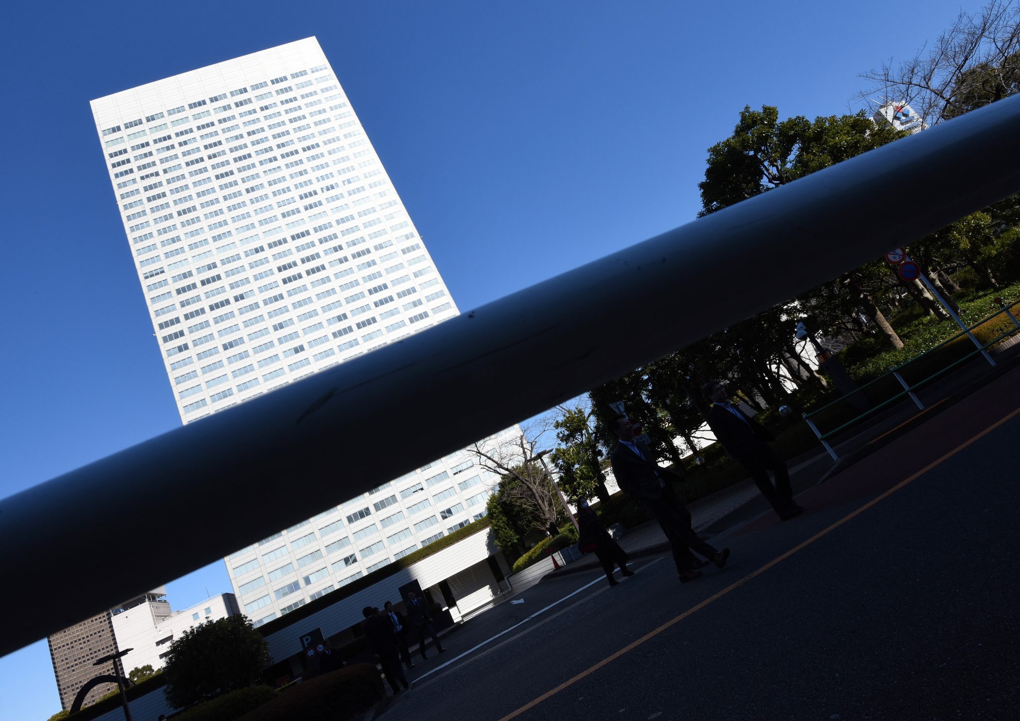 People walk past the headquarters of Japan's Toshiba in Tokyo on February 14, 2017. Toshiba shares dived more than nine percent on February 14 after it surprised markets by delaying the release of financial results that were expected to include billions of dollars in losses tied to its US nuclear power unit. / AFP PHOTO / Toru YAMANAKA