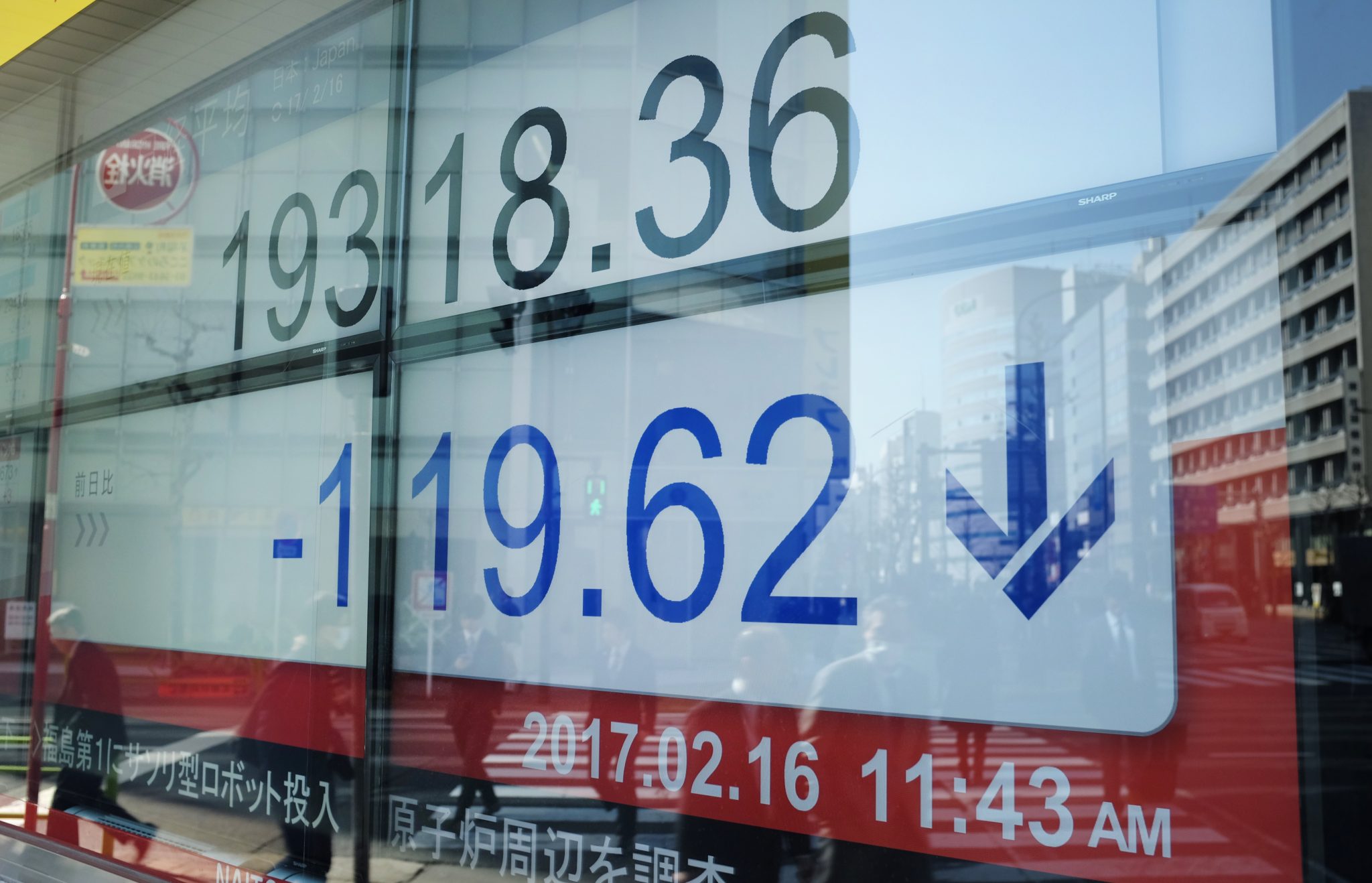 An electric quotation board flashing the Nikkei key index of the Tokyo Stock Exchange is displayed at a securities company in Tokyo on February 16, 2017. The Toshiba Corporation logo is seen at the company's headquarters in Tokyo on February 16, 2017. Shares in Toshiba fell 1.95 percent to 205.6 yen after losing 16 percent the previous two days as fears mount over massive losses from its US nuclear power business. / AFP PHOTO / KAZUHIRO NOGI
