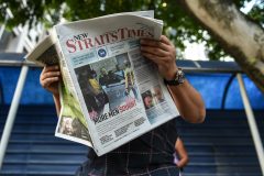 A journalist reads a newspaper with reports about the killed of North Korean man suspected to be Kim Jong-Nam, half-brother of North Korean leader Kim Jong-Un outside the Forensic department at Kuala Lumpur Hospital in Kuala Lumpur on February 17, 2017.   Malaysia will return the body of the half-brother of North Korea's leader, the country's deputy prime minister said on February 16, as police probing the airport assassination arrested a second woman. / AFP PHOTO / MOHD RASFAN