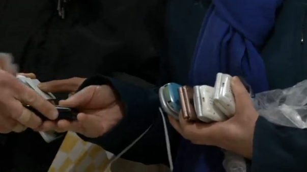 People in Tokyo donate their old mobile phones, which will be recycled into medals for the 2020 Olympic Games. (Photo grabbed from Reuters video)