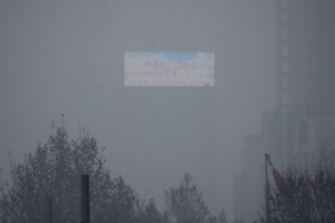 An LED billboard erected on a top of a building is seen through heavy smog in Beijing on January 5, 2017. China has passed a law that levies taxes on pollution, but ignores carbon dioxide, one of the major contributors to global warming, according to the web site of the country's highest legislative body. / AFP PHOTO / WANG ZHAO