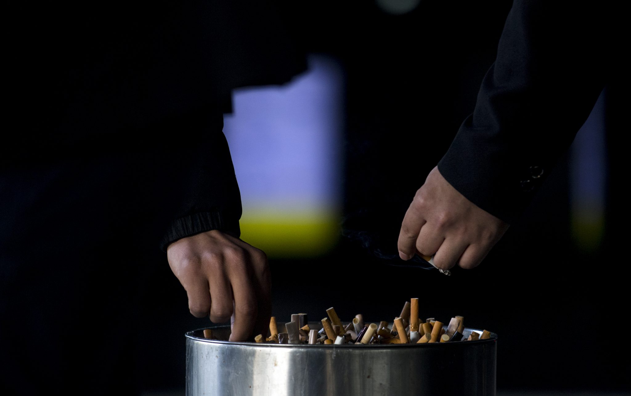 In this photo taken on February 28, 2017, a man grinds out his cigarette in an ashtray at a railway station in Shanghai.   Shanghai widened its ban on public smoking March 1 as China's biggest city steps up efforts to stub out the massive health threat despite conflicts of interest with the state-owned tobacco industry.  / AFP PHOTO / Johannes EISELE