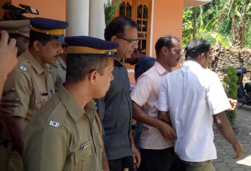 In this photograph taken on February 28, 2017, Indian police officials escort priest Robin Vadakkumchery (C) after his arrest in Peravoor, some 300kms north of Kochin in the southern Indian state of Kerala. Five nuns and a doctor are on the run in India after being accused of concealing the birth of a baby to a teenager who alleges that a priest raped her, police said March 5, 2017. The accused priest Robin Vadakkumchery was arrested last week after the victim gave birth in February, prompting an investigation. Arrest warrants have been issued for the six and for two hospital staff. They are accused of conccealing the 16-year-old's delivery from authorities and hiding the baby in a Catholic orphanage at Kunnur in the southern state of Kerala. / AFP PHOTO / STR