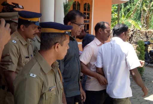 In this photograph taken on February 28, 2017, Indian police officials escort priest Robin Vadakkumchery (C) after his arrest in Peravoor, some 300kms north of Kochin in the southern Indian state of Kerala. Five nuns and a doctor are on the run in India after being accused of concealing the birth of a baby to a teenager who alleges that a priest raped her, police said March 5, 2017. The accused priest Robin Vadakkumchery was arrested last week after the victim gave birth in February, prompting an investigation. Arrest warrants have been issued for the six and for two hospital staff. They are accused of conccealing the 16-year-old's delivery from authorities and hiding the baby in a Catholic orphanage at Kunnur in the southern state of Kerala.  / AFP PHOTO / STR
