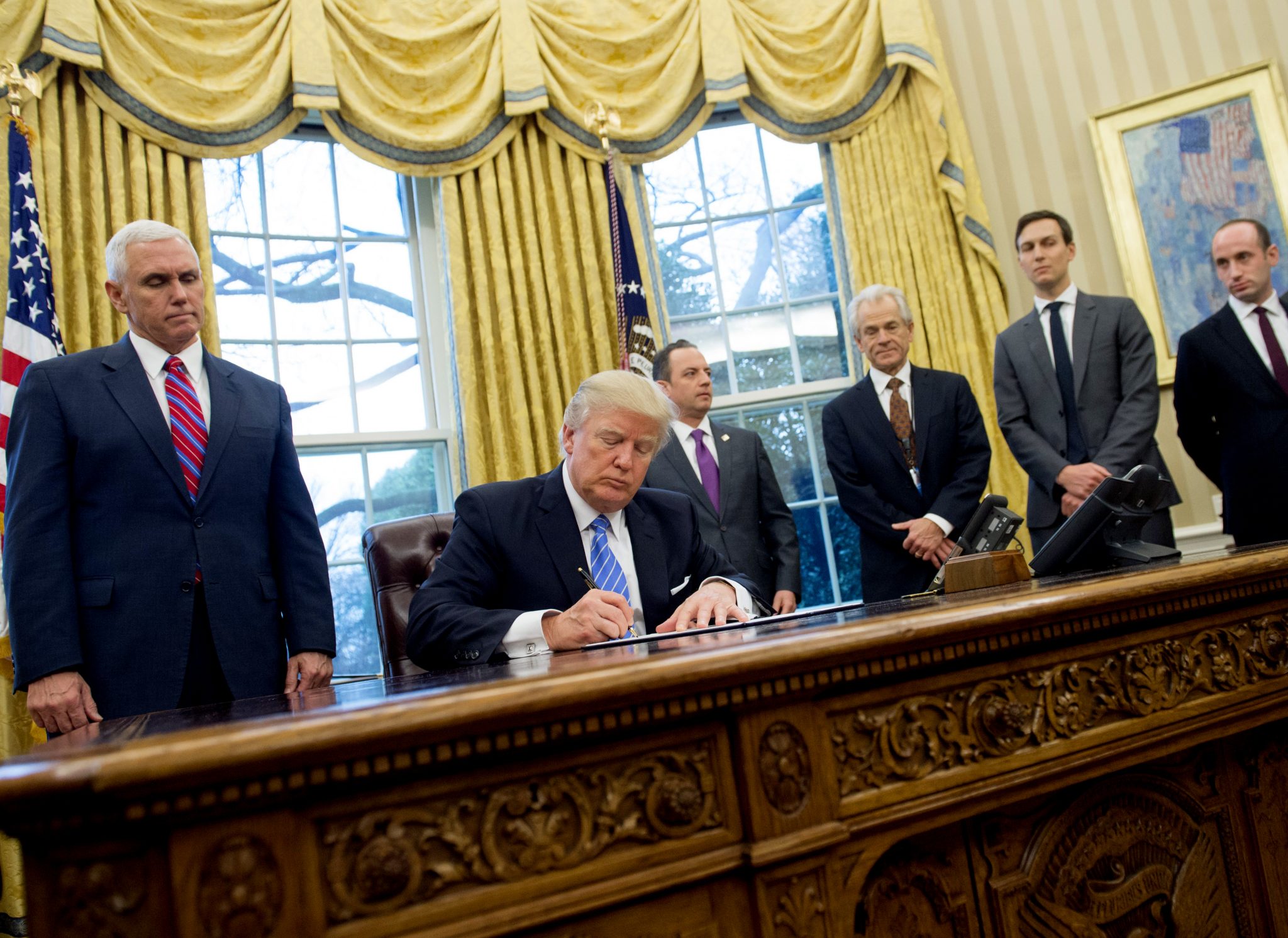 (FILES) This file photo taken on January 23, 2017 shows US President Donald Trump signing an executive order alongside White House Chief of Staff Reince Priebus (C), US Vice President Mike Pence (L), National Trade Council Advisor Peter Navarro (3rd R), Senior Advisor Jared Kushner (2nd R) and Senior Policy Advisor Stephen Miller in the Oval Office of the White House in Washington, DC, January 23, 2017.   The Trump administration's top trade advisor said on March 6, 2017 US trade deficits are a threat to national security that could cause the loss of American freedom and prosperity. Outlining an unapologetically aggressive trade policy, Peter Navarro, director of the White House National Trade Council, accused economists and the media of ignoring the risk posed by trade deficits and embracing an "antiquated view of the world."  / AFP PHOTO / SAUL LOEB