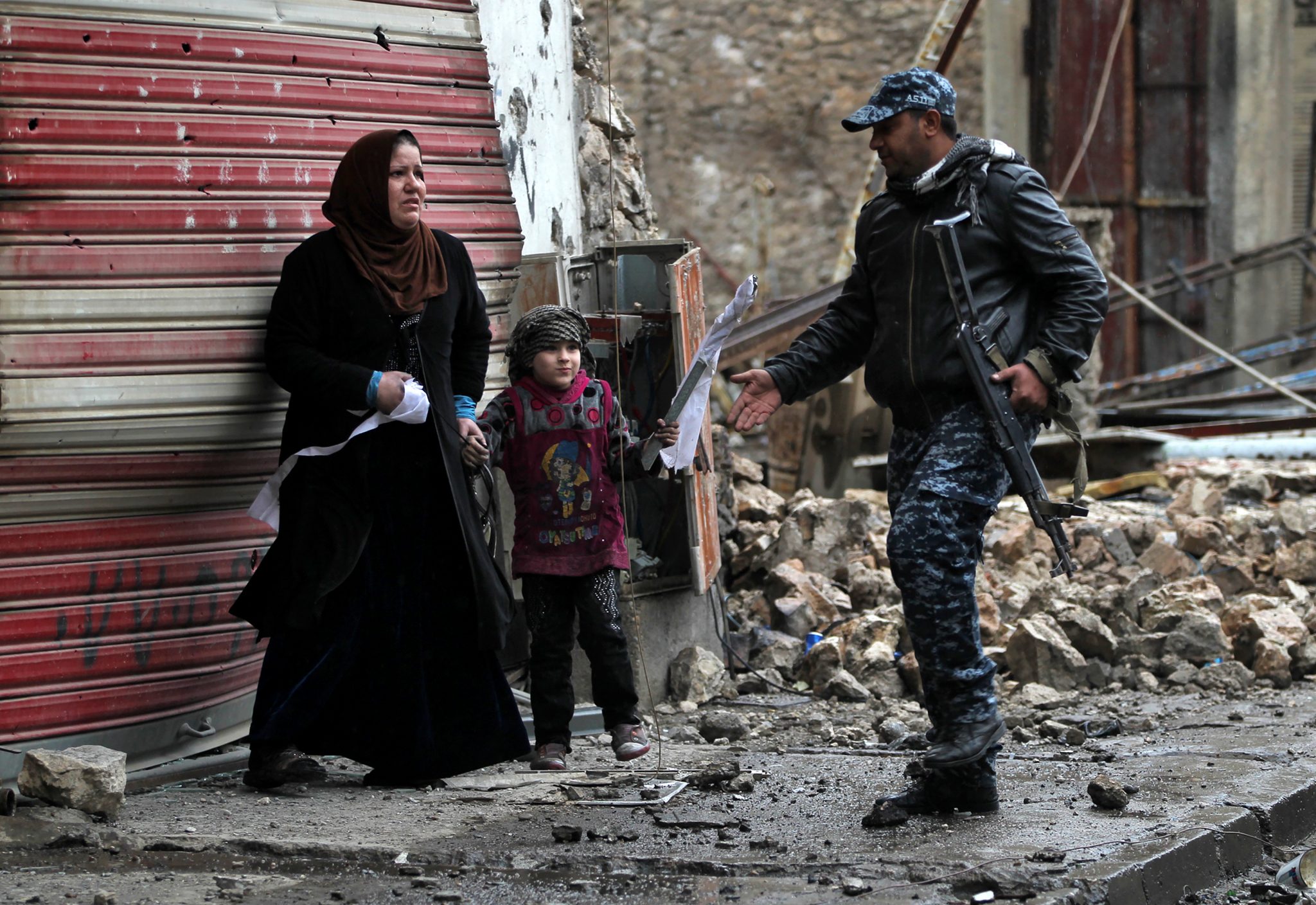 An Iraqi woman and her daughter stand on a street holding white flags as Iraqi forces secure Mosul's Al-Dawasa neighbourhood on March 13, 2017, during an offensive to retake the western parts of the city from Islamic State (IS) group fighters. / AFP PHOTO / AHMAD AL-RUBAYE