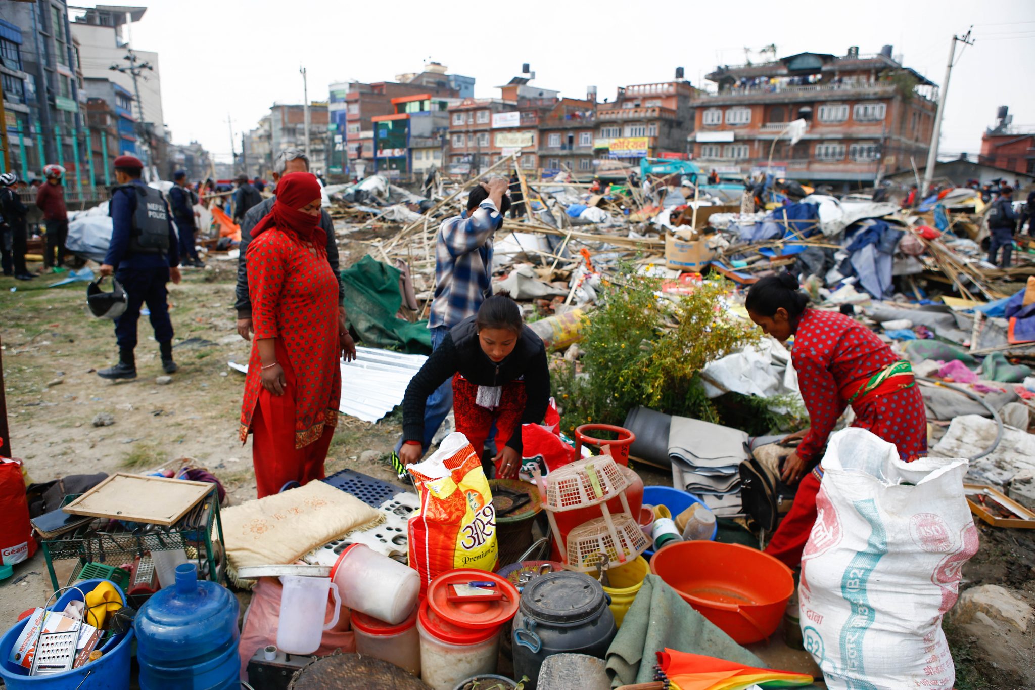 Nepalese homeless people gather their belongings at a makeshift camp for people displaced by the 2015 earthquake after it was demolished by police in Kathmandu on March 14, 2017. Nepal police on March 14 demolished the largest remaining settlement of people displaced by a powerful earthquake that struck nearly two years ago, a move that will leave hundreds homeless. Around 100 families were still living in the camp in Kathmandu when police wearing riot gear used bulldozers to flatten the bamboo and tarpaulin structures. / AFP PHOTO / Sulav SHRESTHA