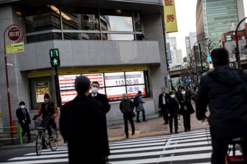 Pedestrians cross a street as an electric quotation board flashes the exchange rate of the Japanese yen against the US dollar in Tokyo on March 17, 2017. Tokyo shares closed slightly higher on March 17 but the gains were capped by a stronger yen after the Federal Reserve hinted at a slower pace of interest rate hikes this year. / AFP PHOTO / Behrouz MEHRI